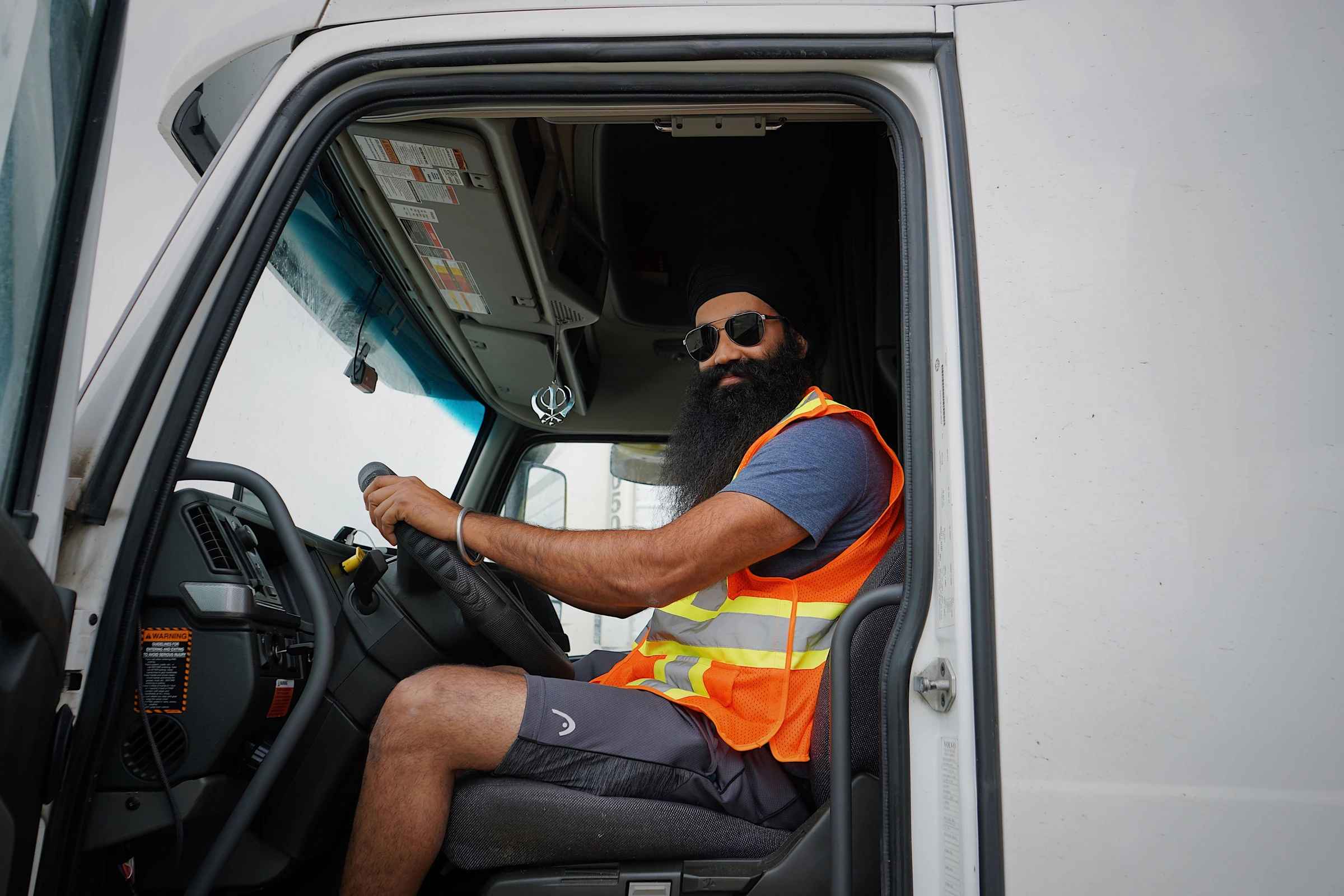 A truck driver in a safety vest seated in his cab