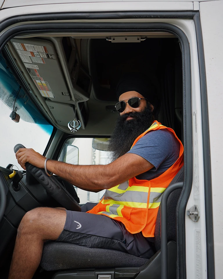 A truck driver in a safety vest seated in his cab