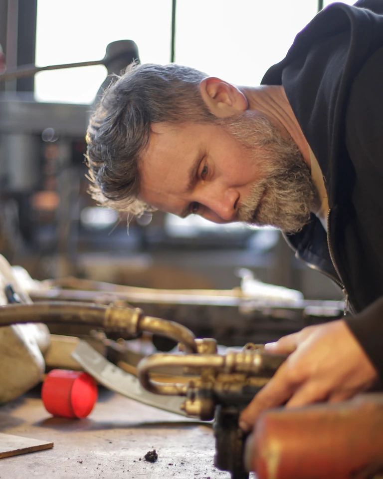 A mechanic working on a metal component at a workbench